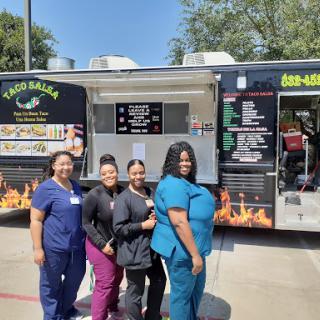 A cheerful group of women enjoying their time at a taco food truck.
