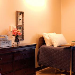 A cozy and inviting bedroom setup featuring a neatly made bed, a decorative cabinet, and fresh flowers.