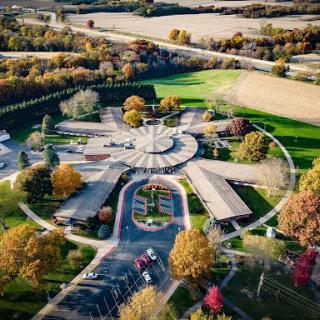 A picturesque aerial view of a building complex surrounded by vibrant autumn foliage.