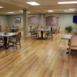 An empty dining area with wooden floors, tables, and chairs.