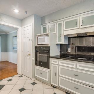 A modern kitchen with white cabinets, featuring a built-in oven and microwave.