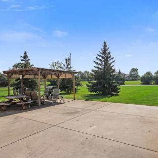 A sunny day in a park with a pavilion and open green space.
