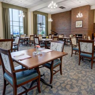 An elegant dining room with neatly arranged tables and chairs, featuring large windows and stylish lighting.