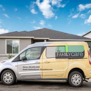 A van with business advertising parked in front of a house under a clear sky.