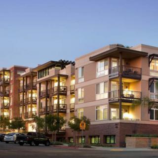 A modern apartment building with balconies, illuminated in the evening.