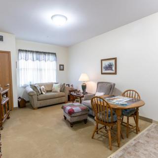 A cozy living room with a sofa, armchairs, and a small dining area.