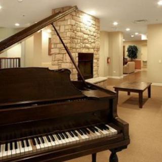 A cozy living room featuring a grand piano and a stone fireplace.