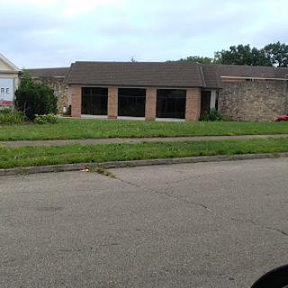 A view of a house with an overgrown front yard.