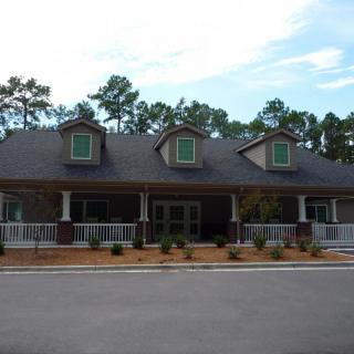 A residential house with a porch and dormer windows, surrounded by trees.
