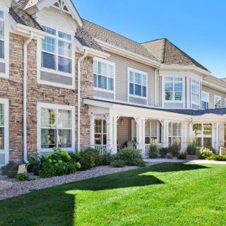 A well-maintained townhouse with a brick facade and lush green lawn.