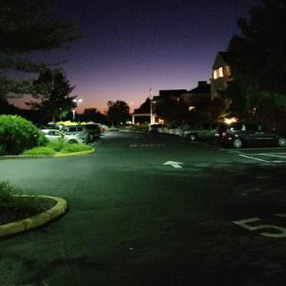 A serene parking lot at twilight, illuminated by soft streetlights.