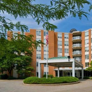 A hotel building with a prominent entrance, surrounded by trees and featuring a flagpole out front.