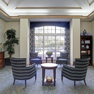 A cozy lobby area with armchairs and a table near large windows.