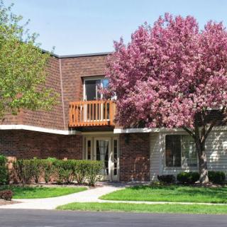 A residential building with a balcony, surrounded by blooming trees in the spring.