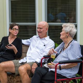 A group of three people engaged in a conversation outside on a patio.