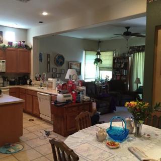 An open-concept kitchen and living space with a dining table, ceiling fan, and various home furnishings.