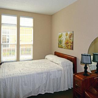A cozy bedroom with a single bed, wooden furniture, and soft lighting.