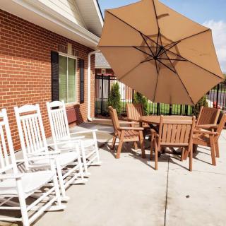 A sunny patio with rocking chairs and a dining set under a large umbrella.