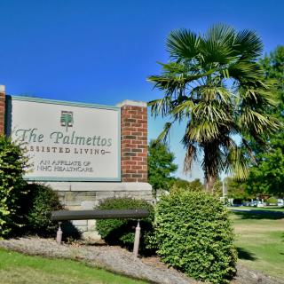 Entrance sign for The Palmetto Assisted Living with a palm tree in the background.