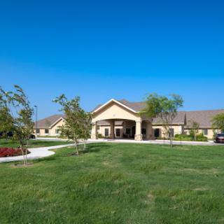 A well-maintained building surrounded by lush green grass and a clear blue sky.