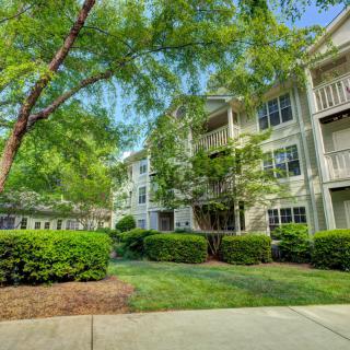 A serene view of a residential apartment complex surrounded by lush trees and well-maintained greenery.