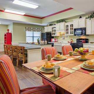 A vibrant kitchen and dining area featuring a colorful table setting with striped chairs and modern decor.