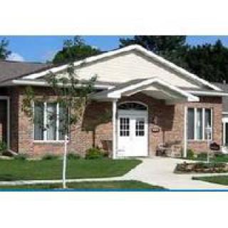 A single-story brick house with a well-maintained front yard and a white door.