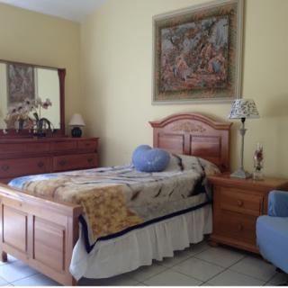 A cozy bedroom featuring a wooden bed, matching nightstand, and warm yellow walls.