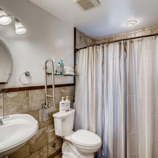 A clean and modern bathroom featuring a round mirror, shower curtain, and neatly arranged toiletries.