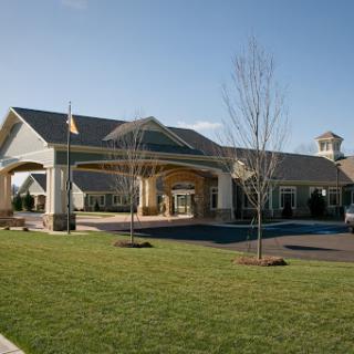 A beautifully designed residential building featuring a welcoming entrance, surrounded by well-maintained landscaping and clear blue skies.