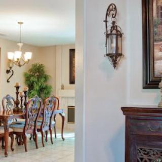 A well-decorated dining room featuring a wooden dining set, chandelier, and artwork on the walls.