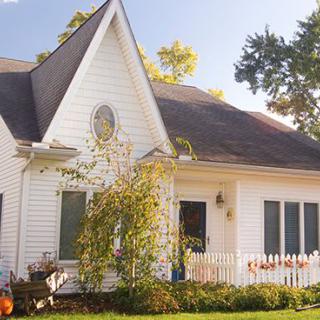 A charming white house with a wooden fence and a small garden on a sunny day.
