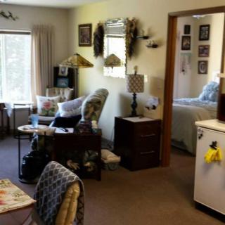 A cozy living room with comfortable seating and a view into the bedroom.