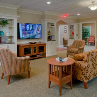 A cozy living room with comfortable chairs, a large television, and built-in bookshelves.