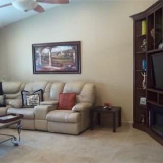A cozy living room with a leather sofa, a large bookshelf, and a wall-mounted television.