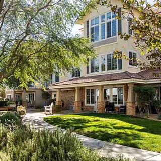 A comfortable residential building with a well-maintained lawn and surrounding trees basking in sunlight.