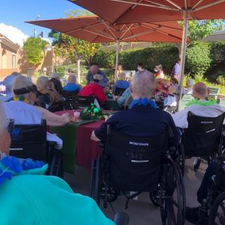 A group of seniors enjoying an outdoor gathering under large umbrellas.