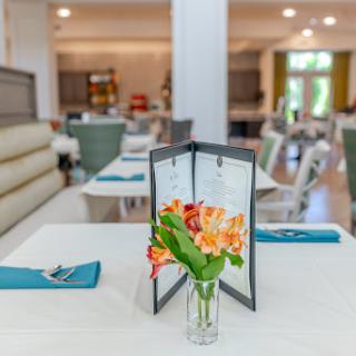 A beautifully arranged dining table with a menu and fresh flowers, showcasing a modern restaurant interior.