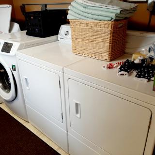 A laundry room with a washing machine, dryer, and a basket of folded clothes.