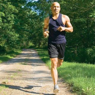 A man jogging on a scenic forest path in the summer.