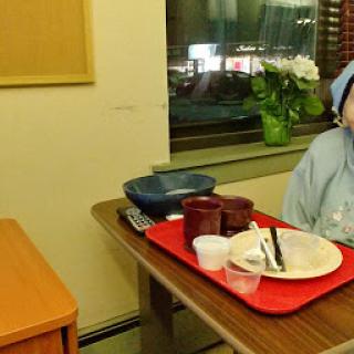 A hospital patient dining alone with a tray of eaten food.