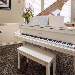 A white piano with a matching bench is elegantly placed in a decorated living room.