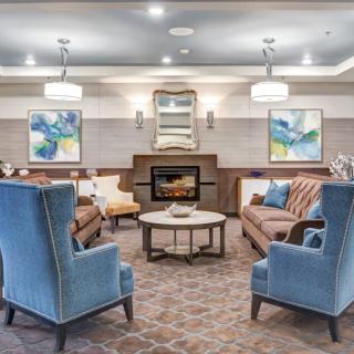 A cozy living room featuring elegant furniture and a central fireplace, adorned with modern artwork and lighting.