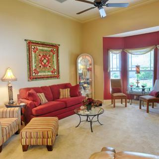 A cozy living room with a red sofa, matching decor, and large windows.