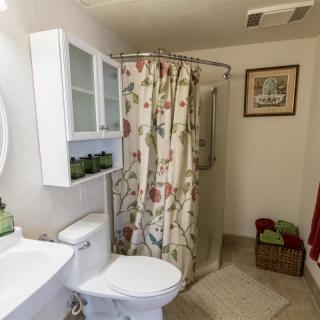 A cozy bathroom with floral shower curtain and neatly arranged towels.