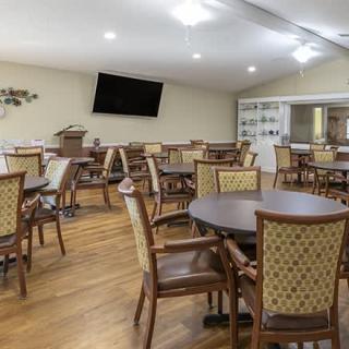 A spacious dining area with several tables and chairs, featuring a wall-mounted television.