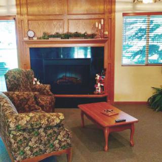 A cozy living room with a fireplace, floral armchair, and wooden coffee table.