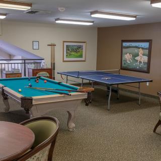 A cozy game room featuring a pool table and a ping pong table, with comfortable seating for relaxation.