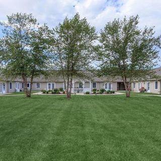A suburban housing complex with a large green lawn and several trees.