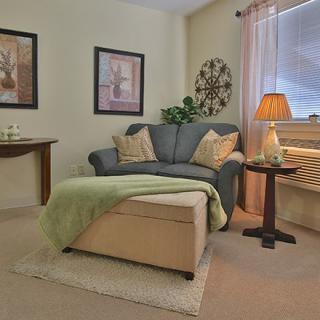 A cozy living room with a sofa, ottoman, and warm lighting.